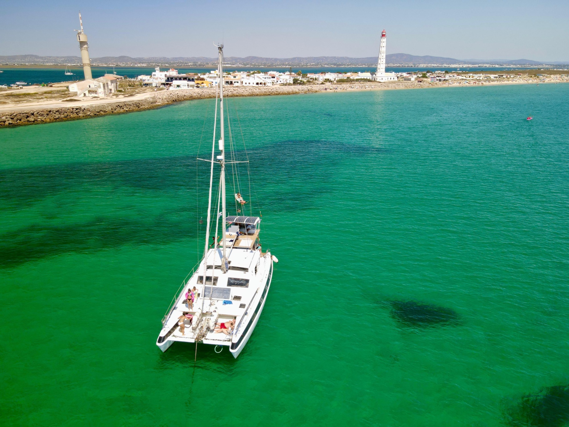 Guests aboard the catamaran anchored near Farol island lighthouse